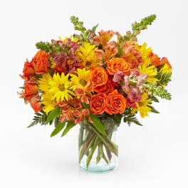 Orange roses and yellow daisies in a clear glass vase