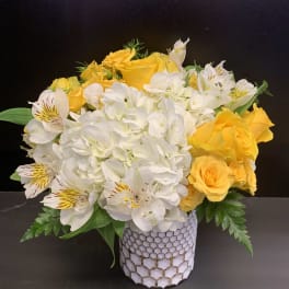 Yellow roses and white hydrangeas in a patterned vase