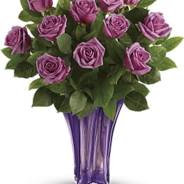 Purple roses arranged in a tall purple glass vase