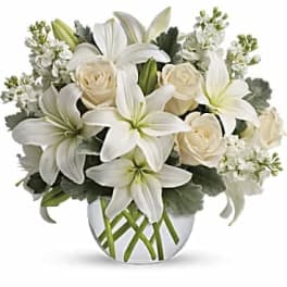 White lilies and cream roses in a clear glass vase
