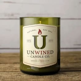 Green glass jar candle with Unwined Candle Co. label on a wooden surface