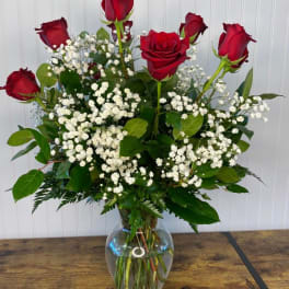 Red roses arranged in a clear glass vase with white baby's breath