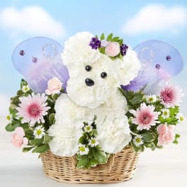 White teddy bear floral arrangement in a wicker basket with purple wings