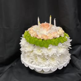 Round floral cake with white chrysanthemums, peach roses, and candles