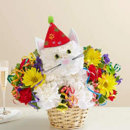 Cat-shaped flower arrangement in a wicker basket with a party hat