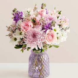 Pink and white mixed bouquet in a purple glass vase