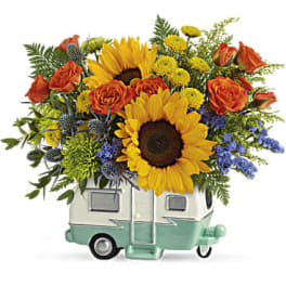 Sunflower and orange rose arrangement in a small camper-shaped vase