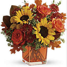 Bouquet of sunflowers and orange roses in a square glass vase