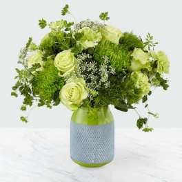 Green and white floral arrangement in a textured vase