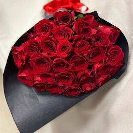 Bouquet of red roses wrapped in black paper with a red ribbon