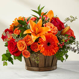 Orange and red flower arrangement in a wooden basket