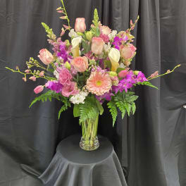 Tall mixed bouquet in a clear glass vase with pink, white, and purple blooms