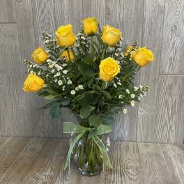 Yellow roses and white daisy spray bouquet in a glass vase with ribbon