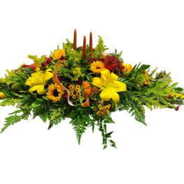Low floral casket spray with yellow blooms and greenery