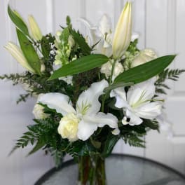 White lilies and roses arranged in a glass vase