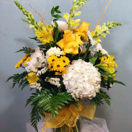 Yellow and white floral arrangement in a glass vase with ribbon