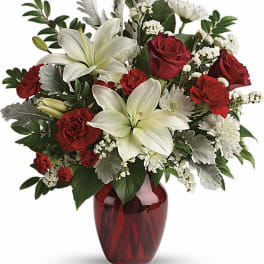 Red roses and white lilies arranged in a red glass vase