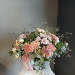 Pastel bouquet of roses, carnations, and small daisies with a pink ribbon