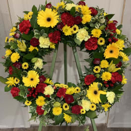 Large circular wreath of red and yellow flowers on a stand