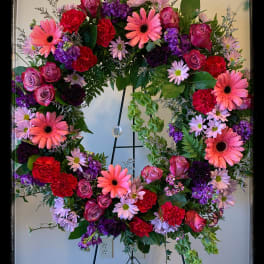 Large floral wreath with pink, purple, and red blooms on a stand
