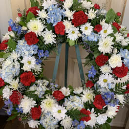 Large floral wreath with red, white, and blue flowers on a stand