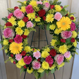 Circular wreath of pink, yellow, and red flowers on a stand
