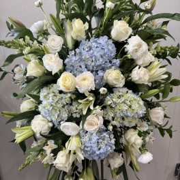 Large standing floral spray with white roses, lilies, and blue hydrangeas