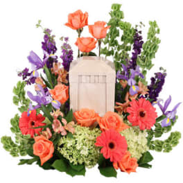 Floral arrangement with orange roses, purple flowers, and a lantern centerpiece