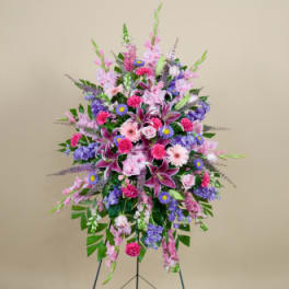 Tall standing spray of pink, purple, and white flowers on a stand