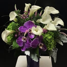 Purple orchids and white calla lilies in a dark vase