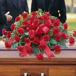 Red floral spray on top of a wooden casket