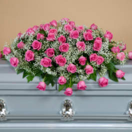 Pink rose casket spray with baby's breath on a light blue casket