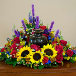 Colorful floral casket spray with sunflowers, red roses, and purple spikes