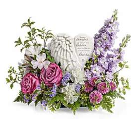 Floral arrangement with pink roses, white blooms, and purple flowers around angel wings