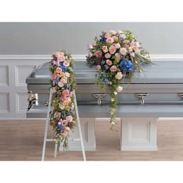 Two pastel floral sprays drape over a silver casket