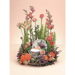 Floral arrangement with roses and snapdragons around a teacup and saucer