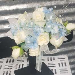 White roses and pale blue flowers arranged with ribbons on a black stand