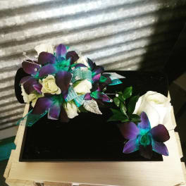 White roses and purple orchids arranged on a black box