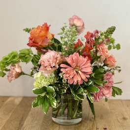 Mixed pink and orange flowers arranged in a clear glass vase