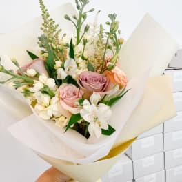 Bouquet of pink roses and white flowers wrapped in cream paper