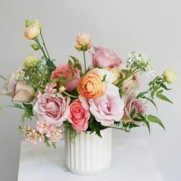 Pink and peach roses arranged in a white vase