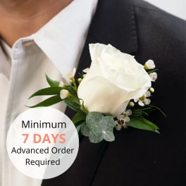 White rose boutonniere with small white blooms pinned to a black suit lapel