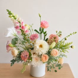 Pastel floral arrangement in a white vase with pink and cream blooms