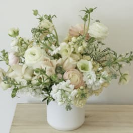 Pastel floral arrangement in a white vase with cream and blush blooms