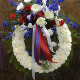 Standing floral wreath with red, white, and blue flowers on an easel