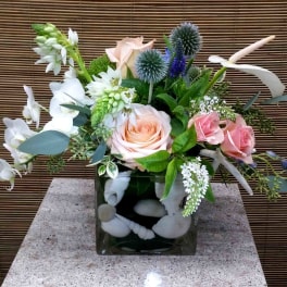 Mixed bouquet with pink roses and white flowers in a square glass vase