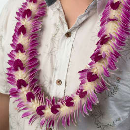 Purple and white orchid lei worn around a person’s neck over a white shirt