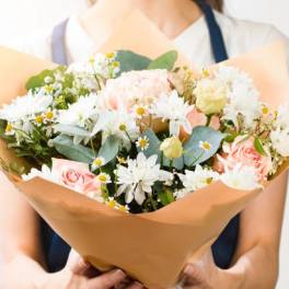 Bouquet of pink roses and white daisies wrapped in tan paper