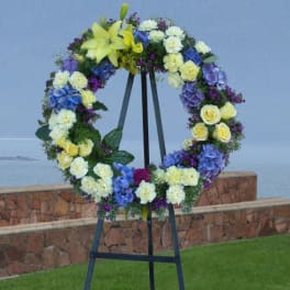 Large floral wreath on a black easel with yellow, blue, white, and purple flowers