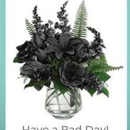 Dark floral arrangement in a clear glass vase with the text 'Have a Bad Day!'